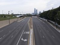 empty highway with skyscrapers in the distance in the background, and trees near the road