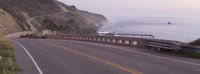 an empty highway next to the beach at sunset overlooking the ocean on cliffs by the water