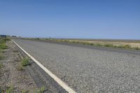 a small, empty highway stretches into the distance with a blue pickup truck behind it