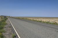 a small, empty highway stretches into the distance with a blue pickup truck behind it