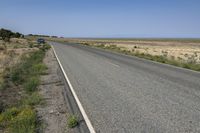 a small, empty highway stretches into the distance with a blue pickup truck behind it