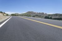 an empty highway surrounded by trees and a mountain range in the background in the distance