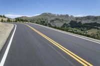 an empty highway surrounded by trees and a mountain range in the background in the distance