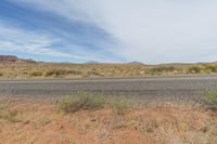 an empty highway surrounded by dry grass and vegetation on an otherwise barren, desert plain