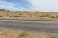 an empty highway surrounded by dry grass and vegetation on an otherwise barren, desert plain