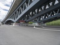 an empty highway, with the underside of a bridge behind it and several large graffiti covered pieces on the side