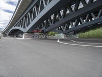 an empty highway, with the underside of a bridge behind it and several large graffiti covered pieces on the side