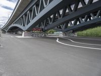 an empty highway, with the underside of a bridge behind it and several large graffiti covered pieces on the side