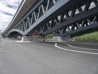 an empty highway, with the underside of a bridge behind it and several large graffiti covered pieces on the side