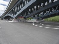 an empty highway, with the underside of a bridge behind it and several large graffiti covered pieces on the side