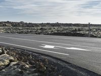 an empty highway on top of rocks with an arrow pointing to the right on the road