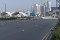 a highway with an empty street going into a big city with tall buildings in the background