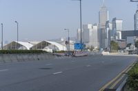 a highway with an empty street going into a big city with tall buildings in the background