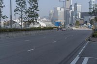 a highway with an empty street going into a big city with tall buildings in the background