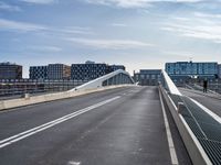 an empty highway has some very long bridges on both sides of it and several buildings