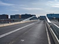 an empty highway has some very long bridges on both sides of it and several buildings