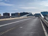 an empty highway has some very long bridges on both sides of it and several buildings