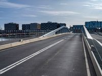 an empty highway has some very long bridges on both sides of it and several buildings