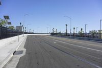 an empty highway with cars traveling on it next to palm trees and buildings in the background