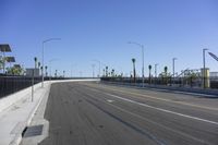 an empty highway with cars traveling on it next to palm trees and buildings in the background