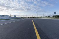 an empty highway with no lanes on it under a partly cloudy sky during the day