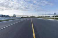 an empty highway with no lanes on it under a partly cloudy sky during the day