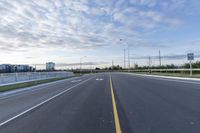 an empty highway with no lanes on it under a partly cloudy sky during the day