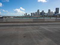 an empty highway in front of the city skylines with cars driving past it on a sunny day