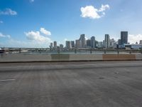 an empty highway in front of the city skylines with cars driving past it on a sunny day