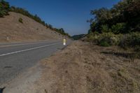 there is an empty highway on this mountain side that appears to be near a hillside