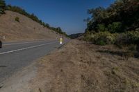 there is an empty highway on this mountain side that appears to be near a hillside