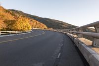 an empty highway windscreens its way through a mountainous valley near some trees and mountains