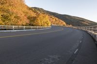 an empty highway windscreens its way through a mountainous valley near some trees and mountains