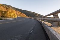 an empty highway windscreens its way through a mountainous valley near some trees and mountains