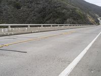 a view of an empty highway with mountains in the background and only the sign on the side