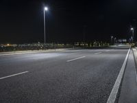 a empty highway in the nighttime on a dark night sky background with several lights, benches and a traffic light at a crossroads