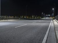 a empty highway in the nighttime on a dark night sky background with several lights, benches and a traffic light at a crossroads