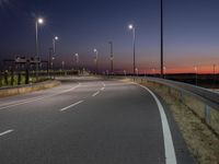 an empty highway near the street with lamps on both sides of it and a few lights are at night