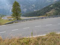 an empty highway with a car going downhill through it and trees in the background in the mountains