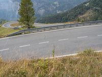 an empty highway with a car going downhill through it and trees in the background in the mountains