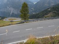 an empty highway with a car going downhill through it and trees in the background in the mountains