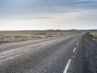 a lone, long empty highway with no traffic on it, stretching across a field