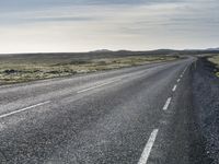 a lone, long empty highway with no traffic on it, stretching across a field