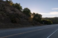 an empty highway with a stop sign in the sunset light behind it and a forest in the distance