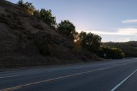 an empty highway with a stop sign in the sunset light behind it and a forest in the distance