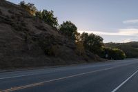 an empty highway with a stop sign in the sunset light behind it and a forest in the distance