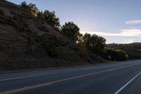 an empty highway with a stop sign in the sunset light behind it and a forest in the distance