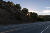 an empty highway with a stop sign in the sunset light behind it and a forest in the distance