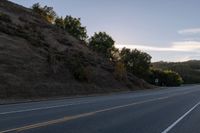 an empty highway with a stop sign in the sunset light behind it and a forest in the distance