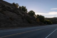 an empty highway with a stop sign in the sunset light behind it and a forest in the distance